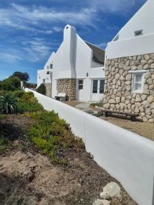 a white house with a stone wall at Zeezicht Villa - Jacobsbaai in Jacobs Bay