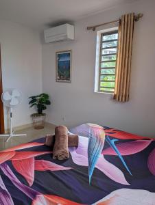 a bed with a colorful blanket with a stuffed animal on it at Manapiti on the hill in Papeete