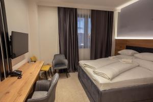 Dormitorio con cama, escritorio y TV en Hotel Sistems, en Banja Luka