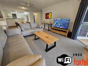 a living room with a couch and a flat screen tv at Fairways Golf & Beach Retreat Bribie Island in Woorim