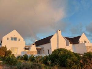 a large white house with a black roof at Zeezicht Villa - Jacobsbaai in Jacobs Bay