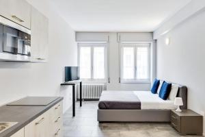 a white room with a bed and a kitchen at Appartamento Mango - Affitti Brevi Italia in Lecco