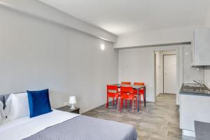 a bedroom with a bed and a kitchen with red chairs at Appartamento Mango - Affitti Brevi Italia in Lecco