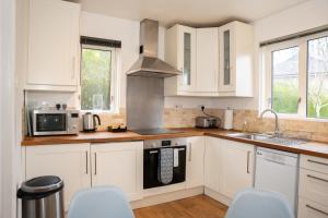 een keuken met witte kasten en een fornuis met oven bij Imagination by Olauda SA - 3 bed House with Free Parking in Bristol