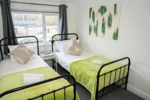 two beds in a room with a window at Imagination by Olauda SA - 3 bed House with Free Parking in Bristol