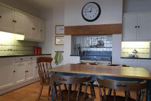 a kitchen with a table and a clock on the wall at Copperpot Cottage 5 mins to the beach! Autumn and Xmas stays booking now in Portrush