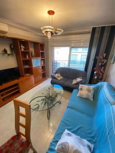 ein Wohnzimmer mit einem blauen Sofa und einem Tisch in der Unterkunft Appartement Spacieux proche commerces et plage Centre-Ville in Roses
