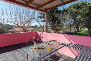 ein Tisch und Stühle auf einer Terrasse mit einer rosa Wand in der Unterkunft Koralia Vacation House in Likotinaréa