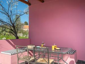 einen Tisch und Stühle an einer rosa Wand in der Unterkunft Koralia Vacation House in Likotinaréa