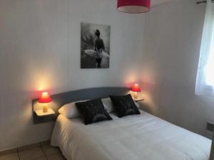 a bedroom with a white bed with two lamps at MAISON Au LAC DU DER '' LES COCCINELLES 41 '' in Giffaumont-Champaubert