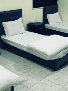 two beds in a room with white sheets at دانية للأجنحة الفندقية in Al Jubayl