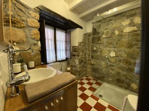 a bathroom with a sink and a stone wall at Vivienda Vacacional La Macona in Infiesto