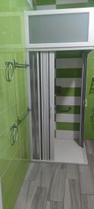 baño con paredes verdes y puerta de ducha de cristal en ALBERGUE EZEQUIEL, en Melide