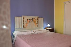 ein Schlafzimmer mit einem Bett mit einem Gemälde darüber in der Unterkunft Donna Lucia in Giardini-Naxos