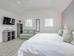 a white bedroom with a large bed and a chair at 4 Bed in Branston 94516 in Branston