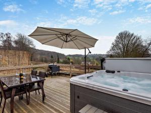 a hot tub sitting on a deck with an umbrella at 2 Bed in Apperknowle 94513 in Unstone