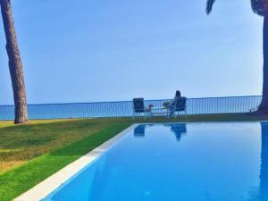 una persona sentada en un banco junto a una piscina en Preciosa casa al borde de un acantilado en Arenys de Mar