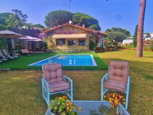 2 chaises assises en face d'une piscine dans l'établissement Preciosa casa al borde de un acantilado, à Arenys de Mar