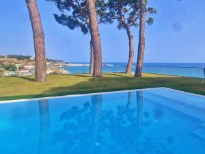 une piscine avec des arbres et l'océan en arrière-plan dans l'établissement Preciosa casa al borde de un acantilado, à Arenys de Mar