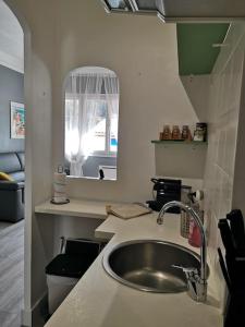 Una pequeña cocina con fregadero y espejo. en Appartement bord de plage, en Cassis