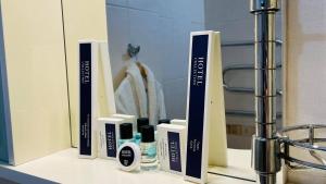 a bathroom counter with a mirror and some products at Tengri Hotel in Atyraū