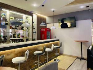 a bar with white stools and a red phone booth at Tengri Hotel in Atyrau