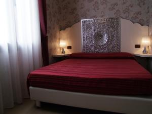 a bedroom with a bed with a red bedspread at Hotel Atlanta Augustus in Venice-Lido