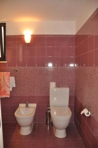 a red tiled bathroom with a toilet and a sink at Donna Lucia in Giardini Naxos