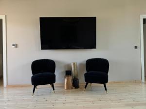- deux chaises noires assises dans une pièce avec une télévision dans l'établissement Amfikleias Earth houses, à Amfikleia