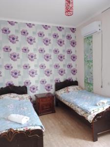 two beds in a room with floral wallpaper at Tamuna Guest House in Martvili