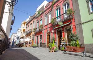 une rue avec des bâtiments colorés, un banc et des tables dans l'établissement Car-Loft next to Arucas Cathedral, à Arucas