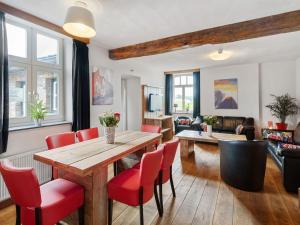a living room with a wooden table and red chairs at Cozy Farmhouse in Bemelen with Terrace in Bemelen