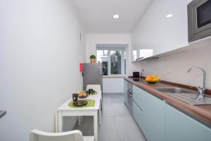 eine weiße Küche mit einer Spüle und einem Kühlschrank in der Unterkunft Scarlatti Garden House - Ap. Charming with Garden in Queluz