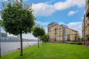 a park with trees and buildings next to the water at Riverview Apartment in Glasgow