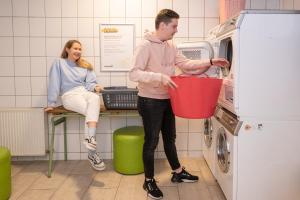 a man holding a basket in front of a microwave at Wombat's City Hostel Budapest in Budapest