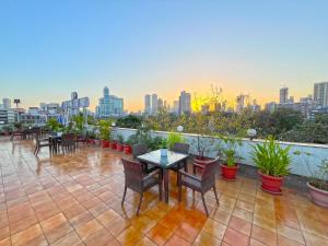 a rooftop patio with tables and chairs and a city skyline at Hotel Parklane in Mumbai