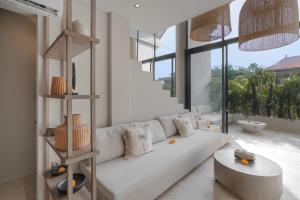 a living room with a white couch and a large window at Loft My Seseh by BaliSuperHost in Canggu