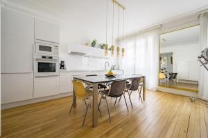 eine weiße Küche mit einem Esstisch und Stühlen in der Unterkunft Magnifique appartement Lumineux in Saint-Mandé