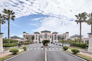 a large building with palm trees in front of a street at Lotte Hotel Jeju in Seogwipo