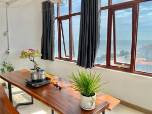 a room with a wooden table with windows at ZoZo House - Homestay Bai Sau 77 in Vung Tau