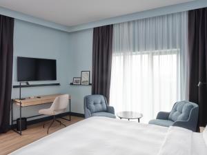 Habitación de hotel con 1 cama, 2 sillas y escritorio. en Radisson Hotel Graz en Graz