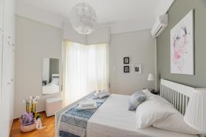 1 dormitorio con 1 cama blanca grande y espejo en Ourania by Heloni Apartments, en Atenas