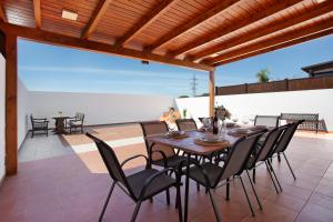 a patio with a wooden pergola and a wooden table and chairs at Villa Zoe in Corralejo
