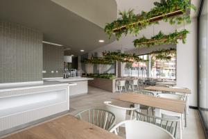 a restaurant with tables and chairs and plants on the wall at AMRO PAMPLONA Residencia de estudiantes in Pamplona