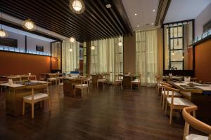 un restaurante con mesas, sillas y ventanas en Swiss-Belinn Doha en Doha