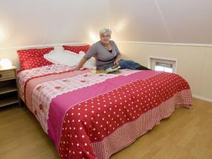 Eine Frau, die auf einem Bett sitzt. in der Unterkunft Cozy house with or without hot tub near a river in Notter