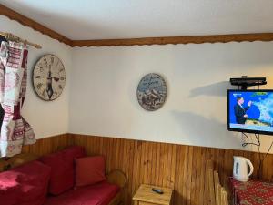 a living room with a couch and two clocks on the wall at La Villaret in Les Menuires