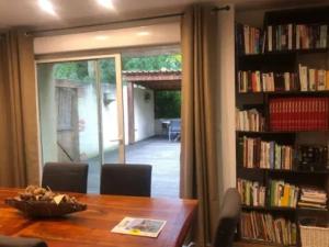 uma sala de jantar com uma mesa e uma prateleira cheia de livros em Villa de 3 chambres avec piscine privee jardin clos et wifi a Gaillac em Gaillac