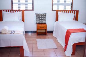 a room with two beds and a table and windows at EAZY BREEZY BACKPACKERS in Dar es Salaam
