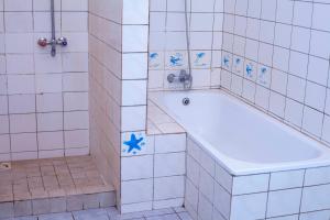 ein weiß gefliestes Bad mit einer Badewanne mit blauen Sternen in der Unterkunft EAZY BREEZY BACKPACKERS in Daressalam